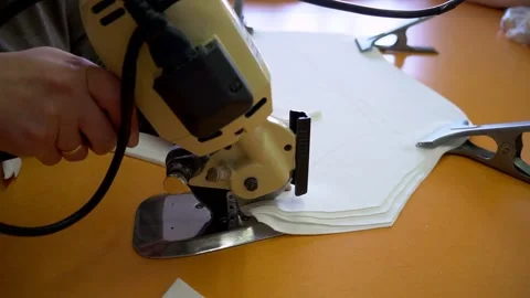 Skilled worker cuts white fabric with electric rotary cutter Stock Footage 136400541