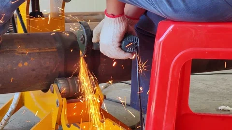 Skilled worker cutting a large circular pipe with a grinder at horizontal Stock Footage 321820969