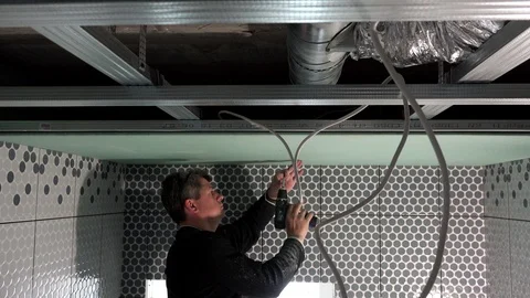 Skilled worker is fixing drywall to ceiling with accumulator screwdriver Stock Footage 123401462