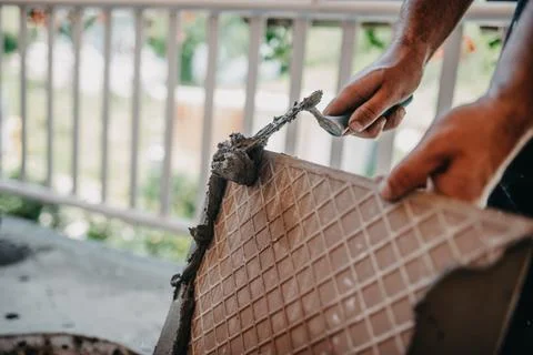 Skilled worker installing the ceramic wood effect tiles on the floor Worker m Foto stock