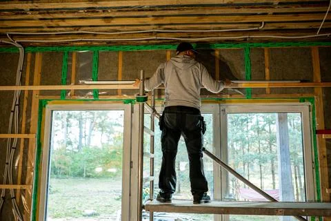 Skilled worker installing windows in a new construction with exposed insula.. Stock Photos