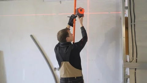 Skilled worker installs device with red laser ray on support Stock Footage 108583099