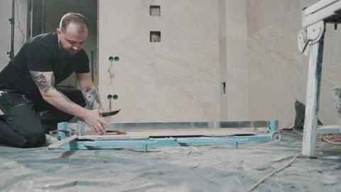 Skilled worker laying tile with precision in a modern workspace Stock Footage 317376543