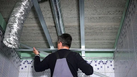 Skilled worker man fasten ceiling profiles in new flat room Stock Footage 120894109