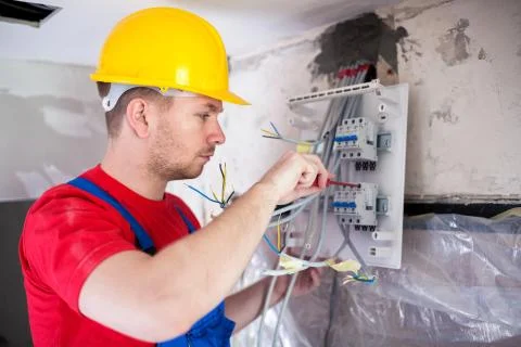 Skilled worker mounting automatic switches on distribution board Stock Photos