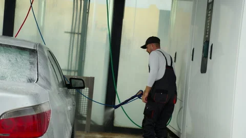 Skilled worker in overalls meticulously wash car use powerful water sprayer.. Stock Footage 320889556