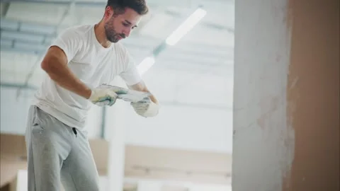A Skilled Worker Perfects a Wall Finish with Precision in a Brightly Lit Space 스톡 동영상 316063257