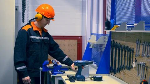 Skilled worker in protective gear operating machinery in workshop. Issues of Stock Photos