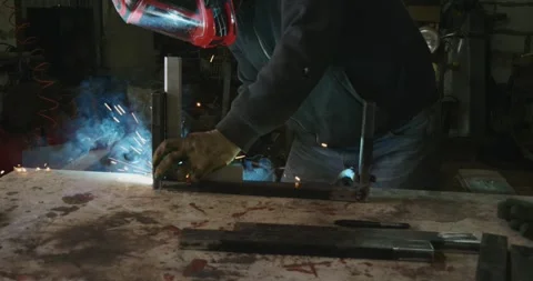 Skilled worker in protective gear using a welding machine to join metal Stock Footage 330782363