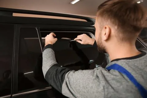Skilled worker tinting car window in shop Stock Photos