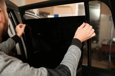 Skilled worker tinting car window in shop Stock Photos