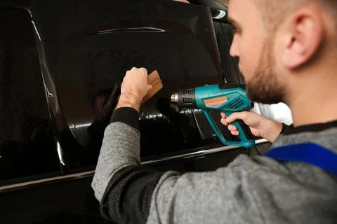 Skilled worker tinting car window in shop Stock Photos