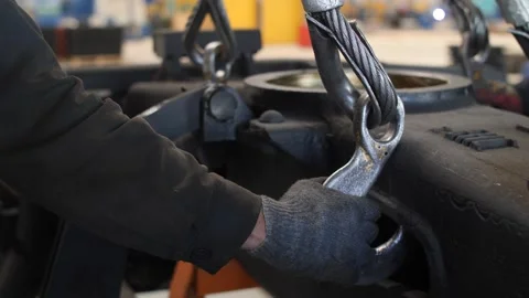 Skilled worker unpins lifting hook from heavy metal part in industrial factory. Video stock 313815350