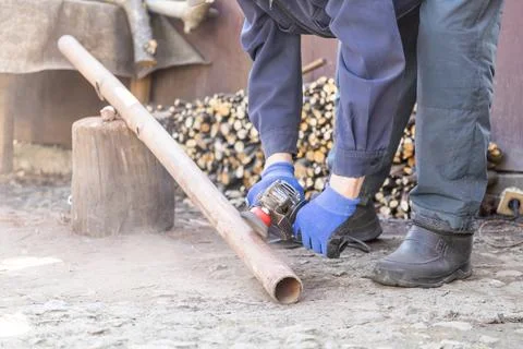 A skilled worker uses an electric angle grinder to sand a metal pipe outdoo.. Stock Photos