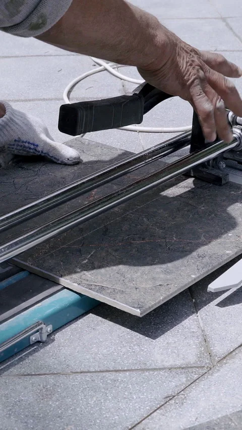 Skilled worker using a cutting tool to shape tiles on a construction site Stock Footage 313929486