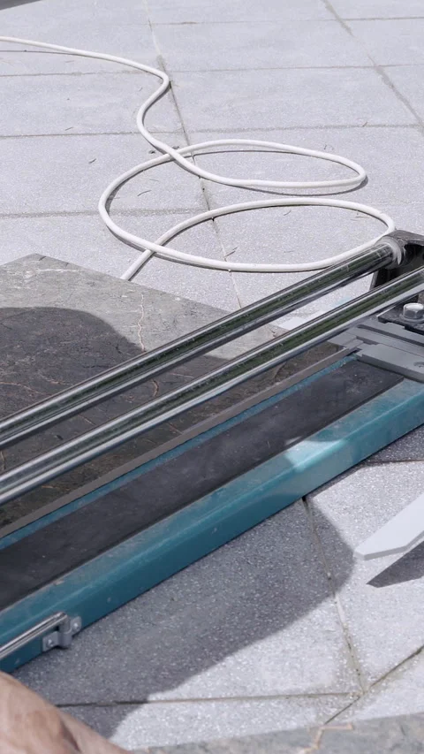 Skilled worker using a tile cutter tool on a stone surface, demonstrating Stock Footage 313927734