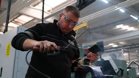 A skilled worker is using a tool to manipulate metal parts in a workshop Stock-Footage 325336609