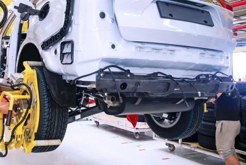 Skilled workers install various components on a vehicle at a bustling automot Stock Photos