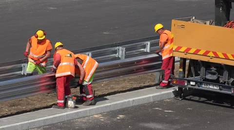 Skilled workers men brigade install safety barrier between freeway road lane Stock Footage 68758309