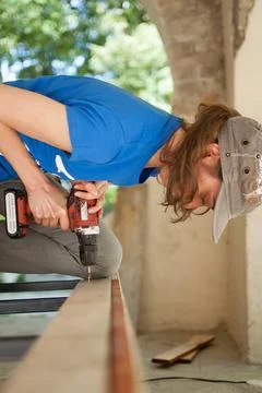 Skilled young female worker is using power screwdriver drilling during Foto stock