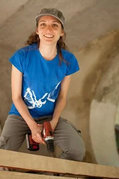 Skilled young female worker is using power screwdriver drilling during Stock Photos