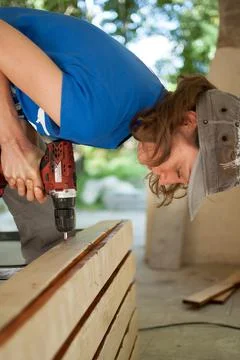 Skilled young female worker is using power screwdriver drilling during Stock Photos