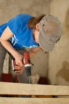 Skilled young female worker is using power screwdriver drilling during Stock Photos