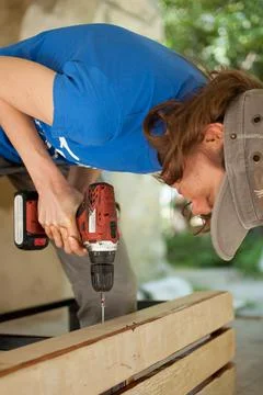 Skilled young female worker is using power screwdriver drilling during Stock Photos