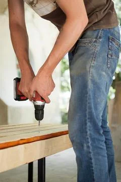 Skilled young male worker is using power screwdriver drilling during Stock Photos