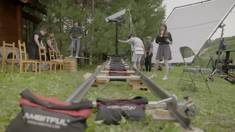 Skillful assistant tests dolly track before camera roll 動画素材 306553001