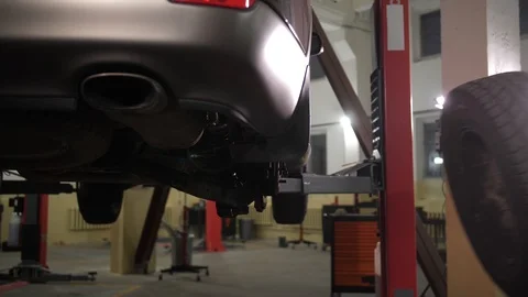 Skillful auto mechanic putting wheel on raised car Stock Footage 123507053