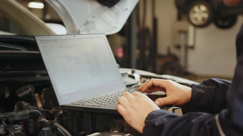 Skillful confident auto electrician using a computer laptop to diagnosing and Stock Footage 243606405