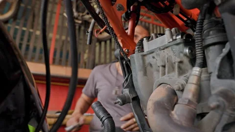 Skillful Engine Restoration: 50 Year Old Asian Woman and Her Orange Motorcycle Stock Footage 258278266