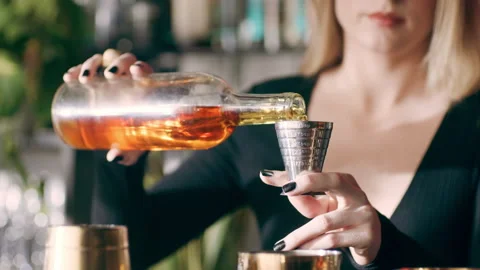 Skillful female bartender pouring a shot of alcohol into a cocktail shaker and s 스톡 동영상 199458142