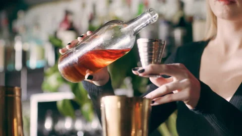Skillful female bartender pouring a shot of alcohol into a cocktail shaker and s Stock Footage 199463518
