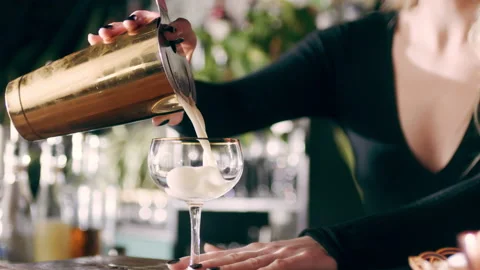Skillful female bartender taking a strainer and pouring the drink into a cocktai Stock Footage 199455734