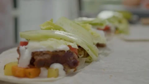 Skillful hands prepare fresh kebab with toppings on soft lavash bread Stock Footage 329269162