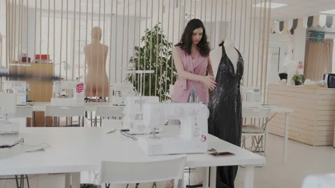 Skillful seamstress checking and tests a trendy evening dress on mannequin Dark Stock Footage 107966712