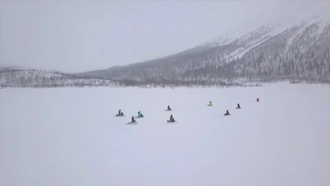 Skillful snowmobile drivers move slowly across valley Video stock 112532990