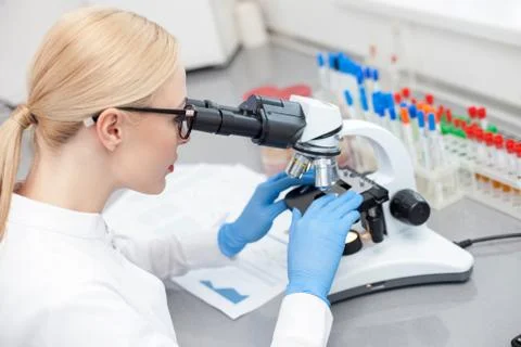 Skillful young laboratory assistant is making closer analysis Stock Photos