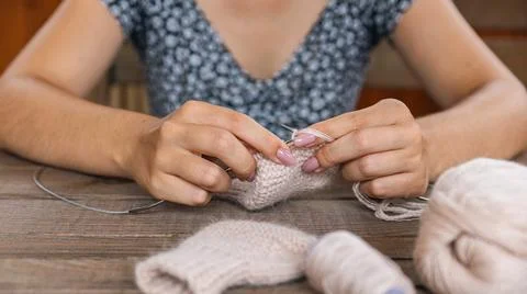 Skillfully knitting a piece using light-colored yarn, perhaps creating a sock Stock Photos