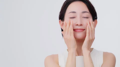 Skin care process. She closes her eyes and puts her hands on her cheek Vidéo 343593390