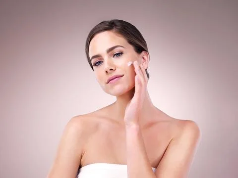 Skin first, makeup second. Studio shot of an attractive young woman applying Stock Photos