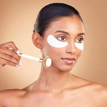 Skincare, eye patch and roller with Indian woman in studio for facial, spa Stock Photos