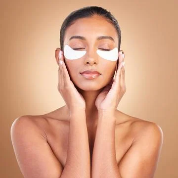Skincare, eye patch and touch with Indian woman in studio for facial, spa Stock Photos