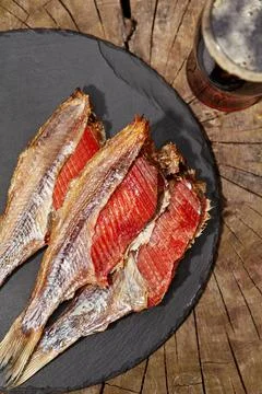 Skinned air-dried roach with roe and glass of dark beer on wooden background Stock Photos