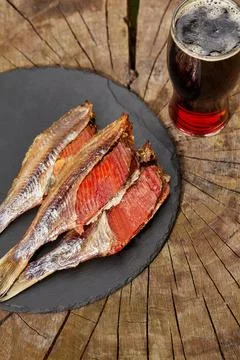 Skinned sun-dried roach with roe and glass of beer on wooden background 스톡 사진