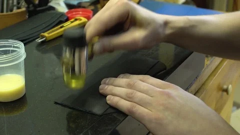 The skinner taps the hammer with a hammer over the glued leather product close Stock Footage 77880540