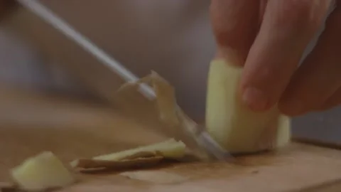 Skinning ginger root on cutting board with a knife Stock Footage 194478558