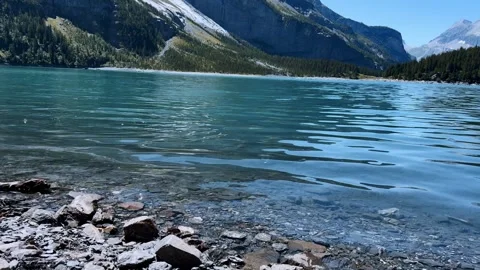 Skipping stones bouncing across turquoise water surface of Lake Oeschinen in Swi Видео 345682864